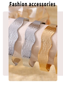 Detailed view of wave-textured open bangles in gold and silver finishes on display