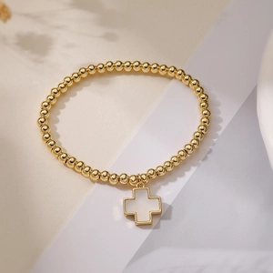 18K gold plated beaded bracelet with white cross pendant on minimalist background