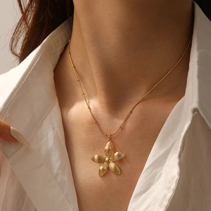 Detail of a vintage gold flower pendant necklace on a delicate collarbone chain