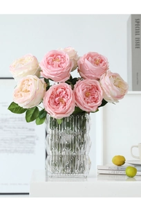 Close-up of realistic pink and white artificial Austin roses in a textured glass vase