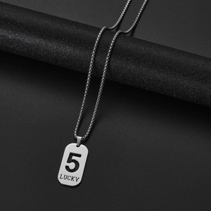 Macro shot of silver stainless steel dog tag pendant with 5 LUCKY engraving