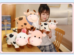 Varios muñecos de peluche de vaca en diferentes colores sostenidos por una mujer