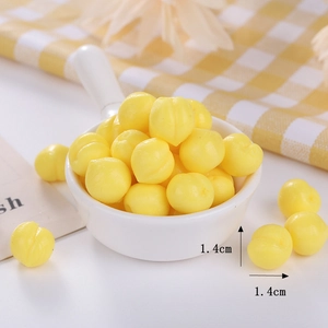 Detailed close-up of 1.4cm mini yellow peach squishy stress toy on checkered fabric