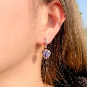 Boucles d'oreilles cœur en or rose avec zircons bleus portées par un mannequin