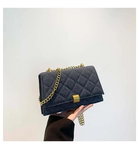 Detail of dark blue quilted denim handbag with gold chain strap and square buckle