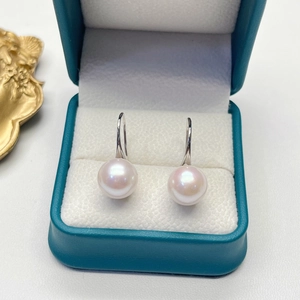Close-up of high-luster freshwater pearl earrings resting in a premium teal jewelry box