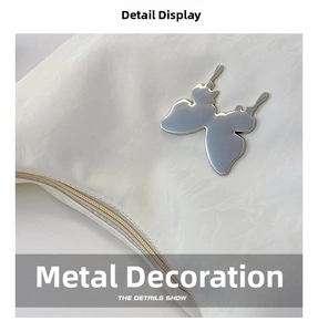 Detailed macro view of white textured leather handbag with a silver butterfly ornament