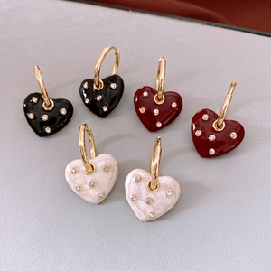 Detailed view of heart charms in black, wine red, and marble white with sparkling crystals