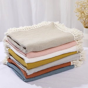 Close-up stack of multi-colored soft muslin cotton baby blankets with tassel trim