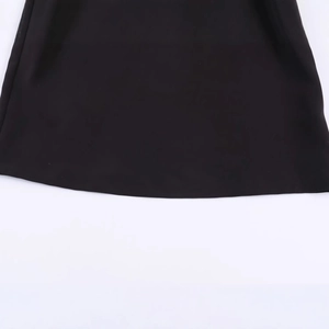 Close-up of black polo top hem showing fine flat weave fabric and stitching details