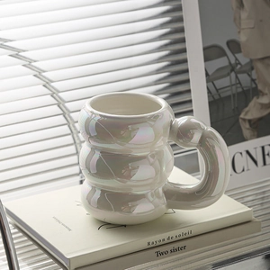 Macro view of pearlescent white ceramic mug with unique three-tier lantern shape and round handle