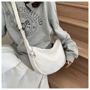 White corduroy crossbody bag styled with a cute puppy pendant on a casual model outfit