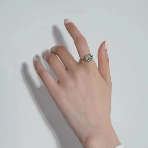 Close-up of golden spinning planet ring with colorful crystals on a model finger