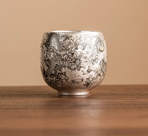Détail macro d'une tasse en argent ornée de motifs complexes de dragons et nuages