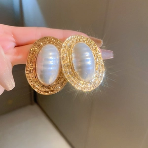 Macro detail of vintage oval pearl earrings with gold textured borders and ribbed design