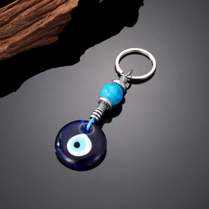 Detail of blue glass evil eye keychain with blue beads and metallic ethnic ornaments