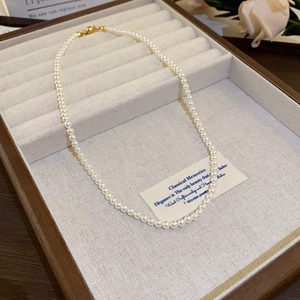 Detailed view of oval white pearls with a golden metal clasp on a jewelry tray
