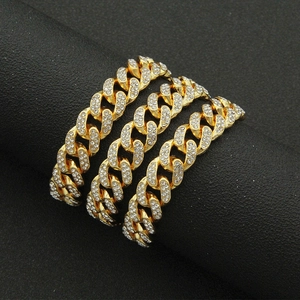 Close-up of three gold-plated 13mm Cuban link chains with iced-out pave crystals on a cylinder