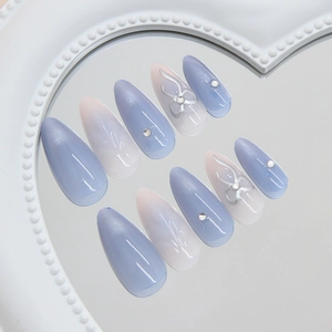 Blue cat-eye press-on nails with silver 3D bows and rhinestones in long stiletto shape