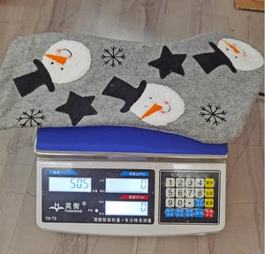 Detailed view of a grey Christmas stocking on a digital scale weighing 50.5 grams