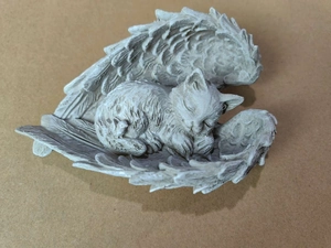 Sleeping cat resin sculpture wrapped in angel wings on craft paper background