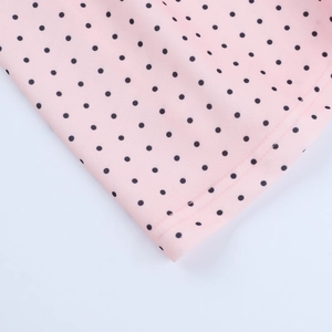 Macro shot of double-stitched hem on pink fabric with black polka dot print pattern