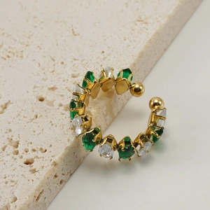 Detail of a C-shaped ear cuff with emerald and clear crystals on a gold-plated base