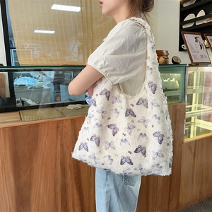 Detailed view of the white tote bag featuring purple butterfly prints and feather texture