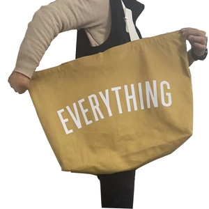 Detail of spacious yellow canvas tote bag with bold white Everything lettering on the front