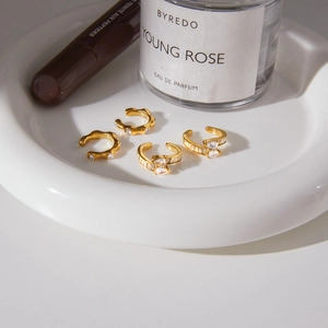 Four gold ear cuffs with pear-shaped cubic zirconia in a luxury scene display