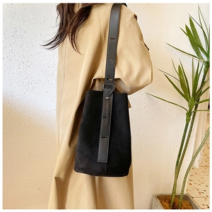Detail of black suede bucket bag with adjustable wide shoulder strap on model