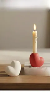 Close-up of minimalist heart-shaped ceramic candle holders on a wooden desk setup