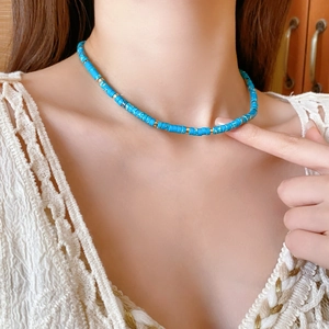 Detail of round blue Shoushan stone necklace with gold beads on model neck