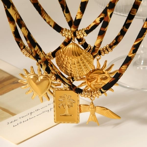Detail von Leopardenmuster-Stoffband und goldenem Herz-Muschel-Sonnenanhänger