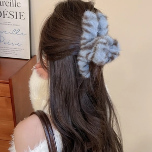 Detail view of a blue-grey plush hair claw clip with a stylish striped velvet texture