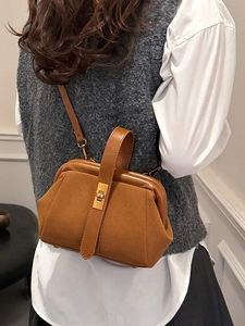 Retro brown shell-style crossbody handbag with gold buckle shown on a model