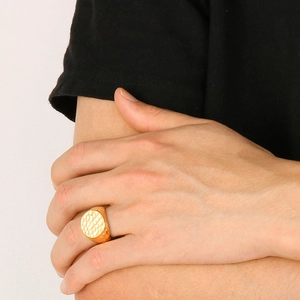 Close-up of a wide gold stainless steel ring with a hammered texture on a model hand