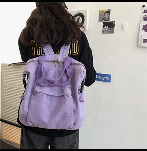 Detailed back view of a purple washed canvas backpack with front zip pocket and straps