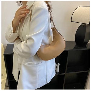 Detail view of a beige crescent underarm bag with smooth leather finish and silver zipper