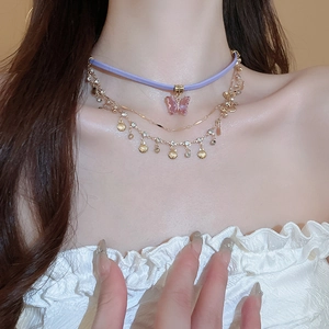 Close-up of triple-layered necklace with pink butterfly and small shell pendants