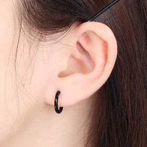 Close-up of minimalist black stainless steel hoop earring worn on a model's ear