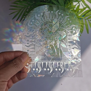 Detailed holographic sun and arch rainbow suncatcher sticker held by hand