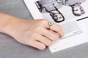 Detail of golden Evil Eye ring on a sparkling silver background for a stylish look