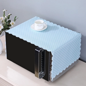 Close-up of light blue polka dot dust cover with wavy lace edges on microwave oven