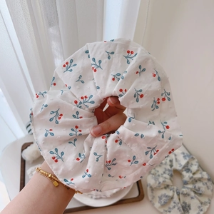 Close-up of a large white cotton scrunchie with red cherry prints and green leaves