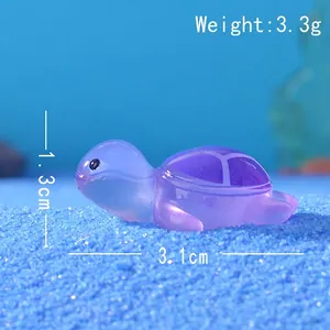 Vista macro di una tartaruga in resina viola lunga 3,1 cm su decorazione di sabbia blu