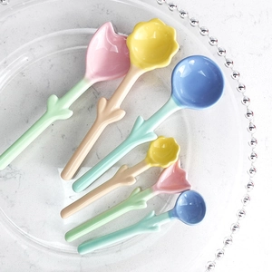 Pastel tulip floral ceramic spoons with green leaf handles on a glass display plate
