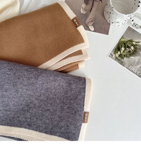 Detailed close-up of soft knitted scarf with contrast trim and branded fabric label