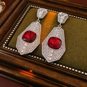 Vintage luxury earrings with square red gemstone and diamond halo on dark velvet