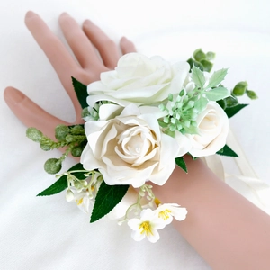 White silk rose bridal wrist corsage with green leaves and ribbon for wedding ceremony